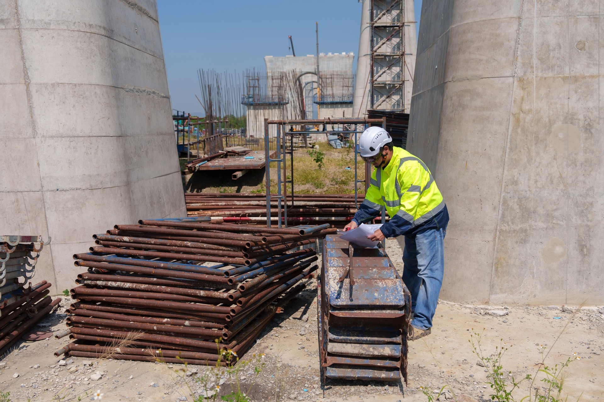 Asian architect engineer wearing safety uniform surveying and working at building structure checking blueprints construction site road general job details business concept architecture street